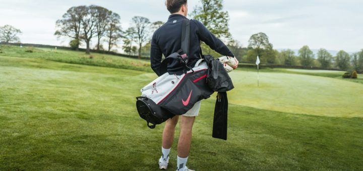 Golfista nesoucí golfový bag s holemi na hřišti