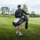 Golfista nesoucí golfový bag s holemi na hřišti