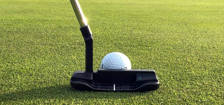 Putter a golfový míček na upraveném greenu
